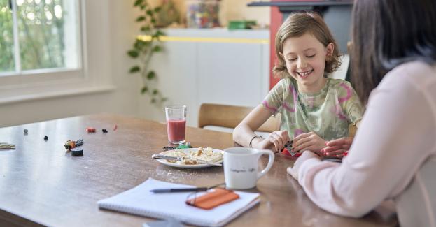 Smiling girl sat at kitchen table with a social worker