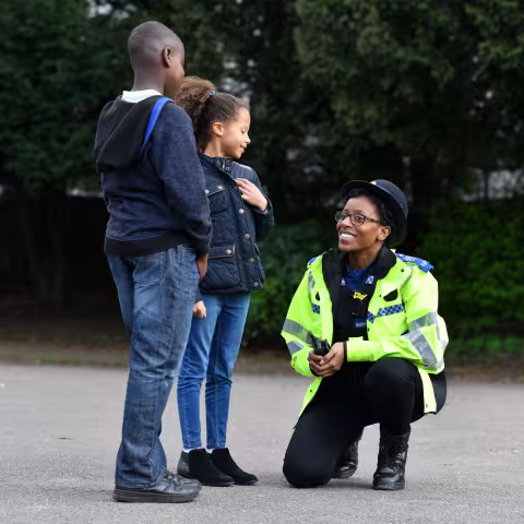 Police officer crouching to speak to two children